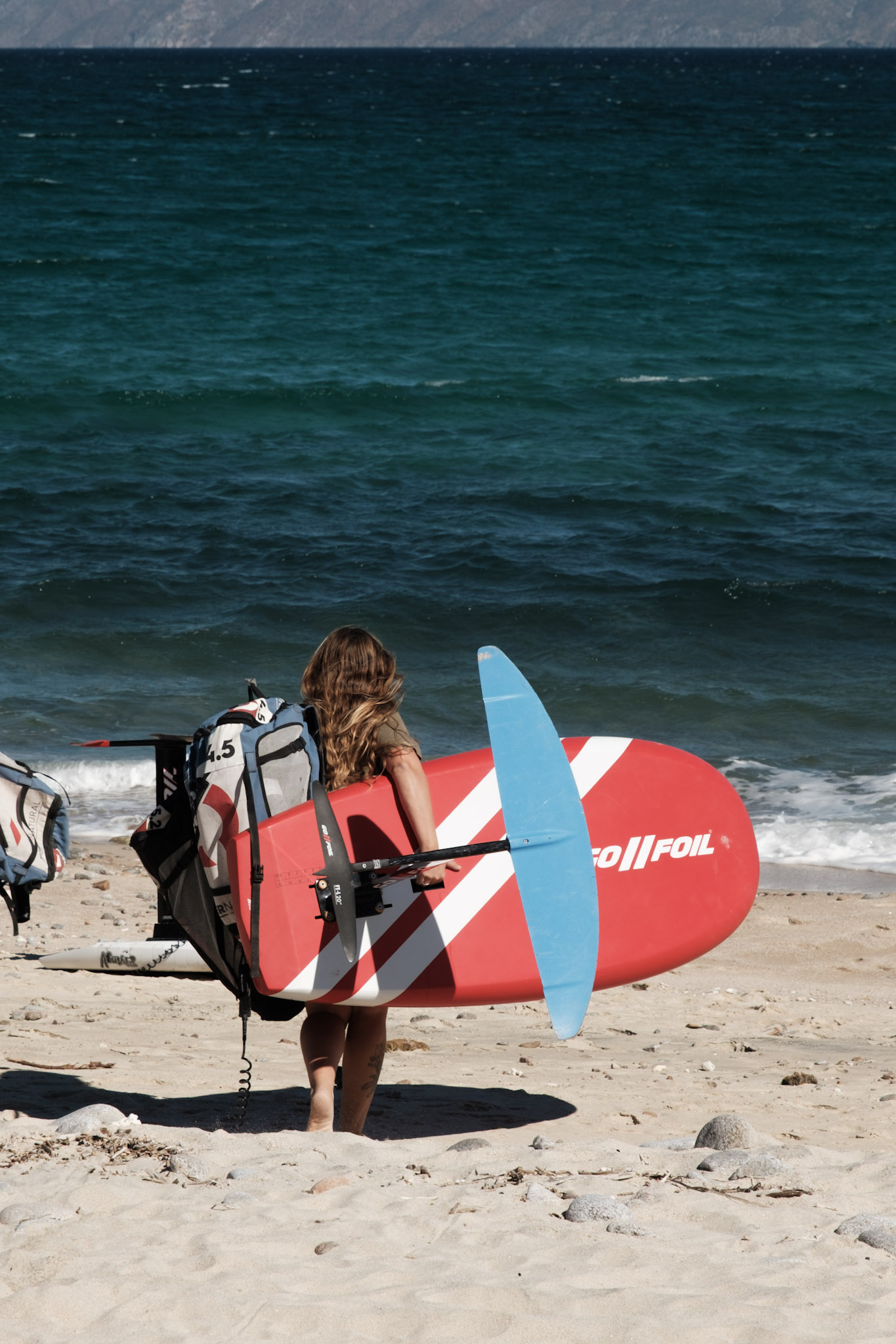 Carrying a board and wing down to the beach