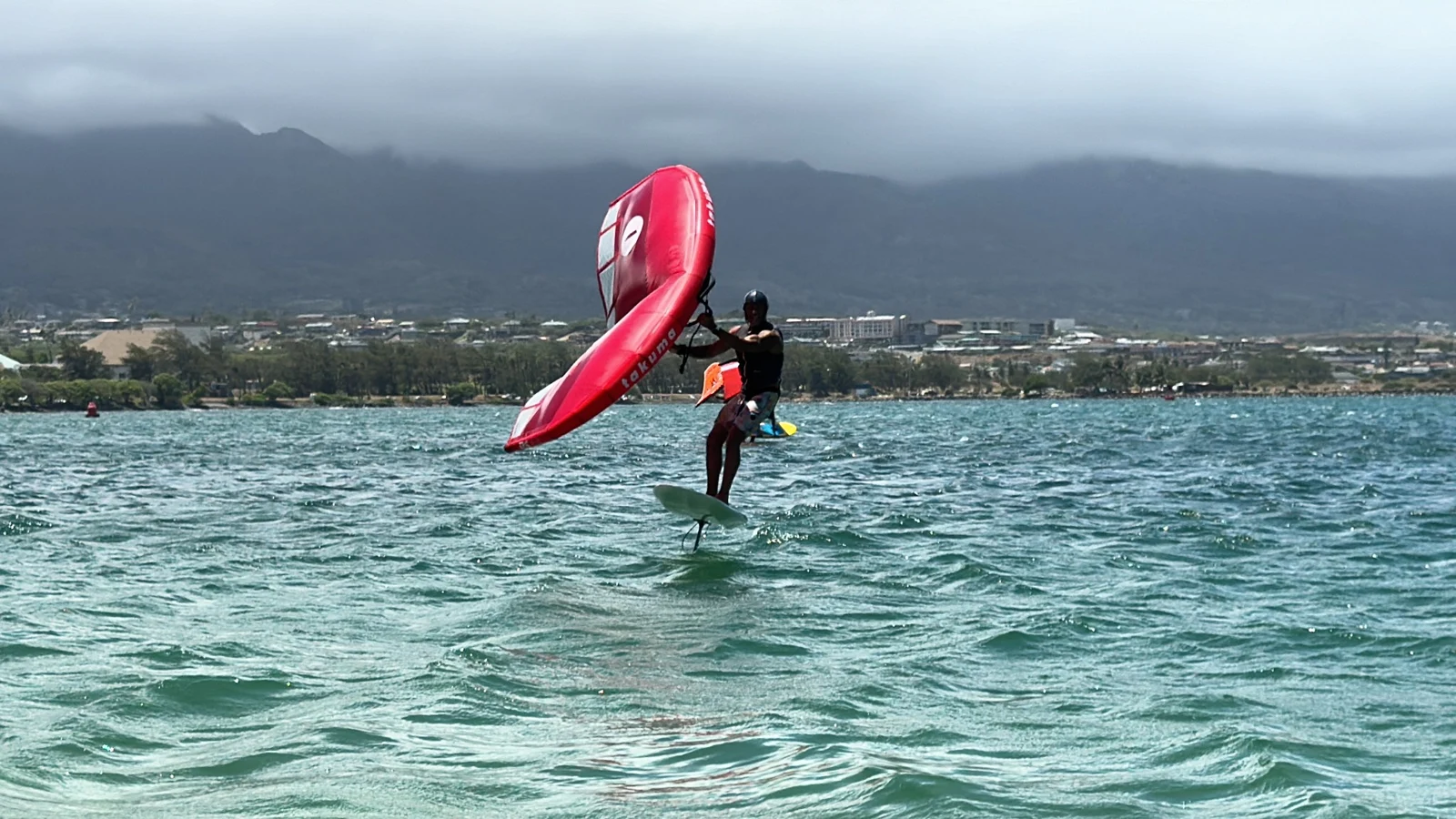 Wing foiler riding with the Maui mountains in the background