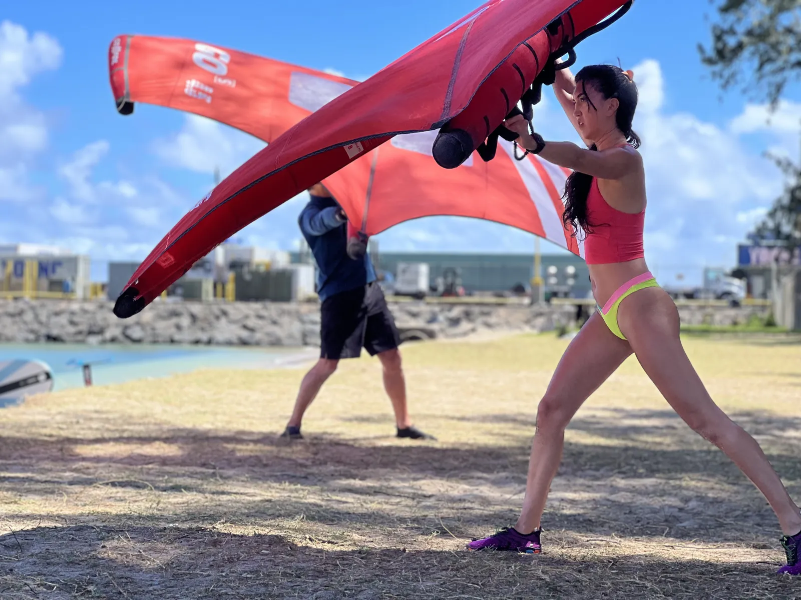 Two riders practicing with red wings on shore in Maui