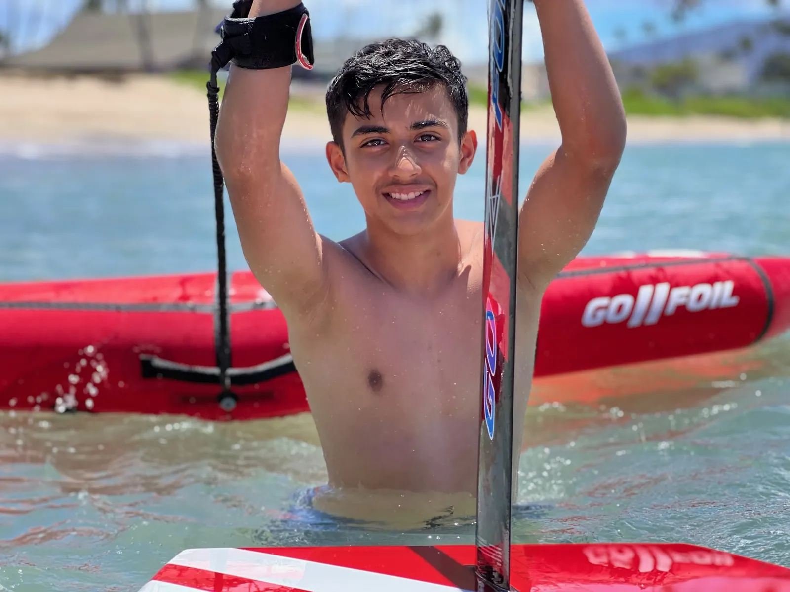 Rider holding a foil board in the water with a red wing behind