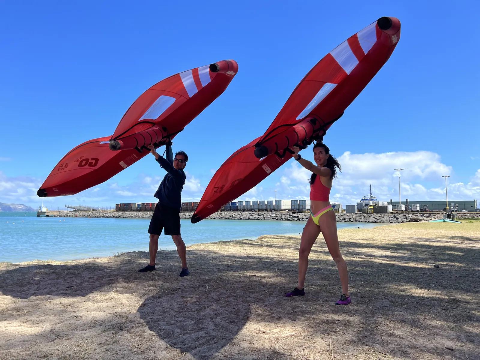 Two riders holding wings overhead during onshore practice