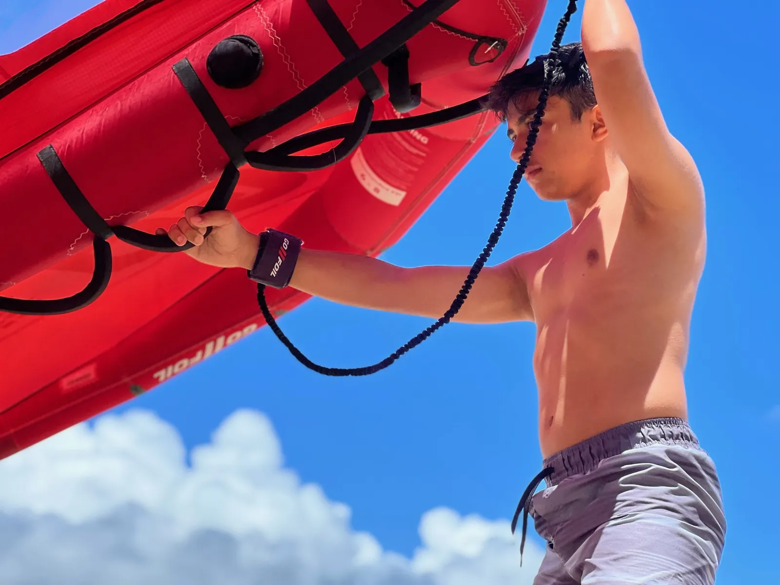 Rider holding a red wing overhead against a blue sky